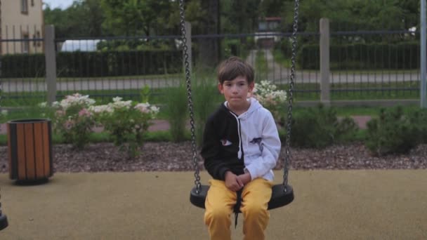A little boy was swinging on a swing. Playground with one child. The boy rested on the swing - Filmati, video