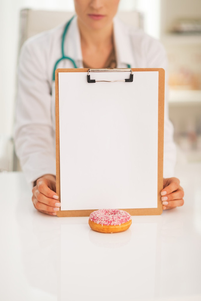 Closeup on doctor woman showing clipboard and donut - Foto, immagini