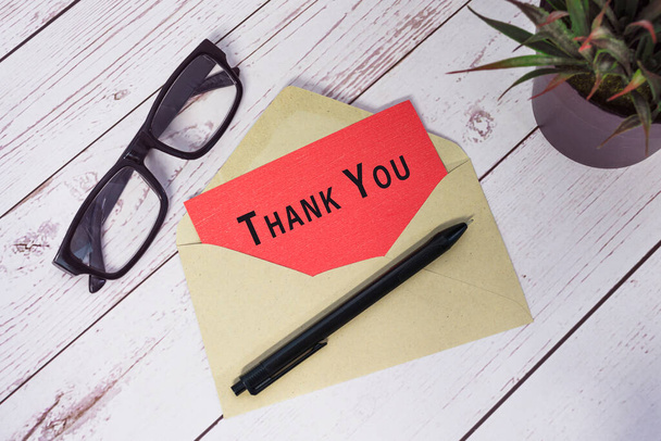Thank you text on red card with envelope on wooden desk. - Foto, Bild
