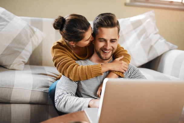 The internet helps us to plan for a brighter future. a young couple using a laptop while relaxing at home - Valokuva, kuva