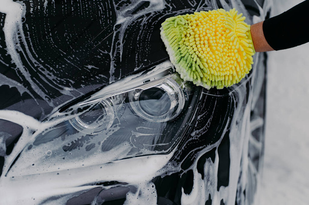 Human hand work concept. Man washes car with soap and cloth. Vehicle cleaning. Close up shot of hand mop washing automobile - Photo, Image