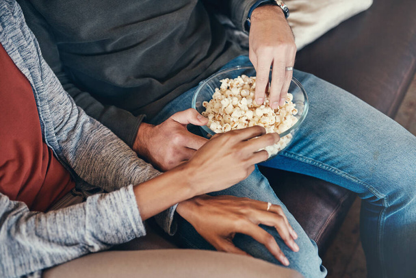 Were couch potatoes this weekend. an unrecognizable couple eating popcorn together while sitting on a sofa at home - Foto, Bild