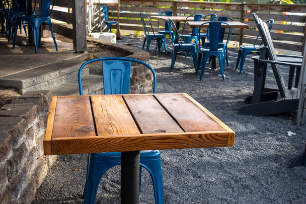 Colorful view of bright blue chairs gathered around a wooden table on an outdoor patio at a restaurant - Foto, Imagem