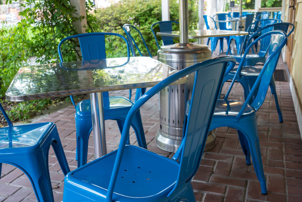 Πολύχρωμη θέα φωτεινό μπλε καρέκλες συγκεντρώθηκαν γύρω από ένα τραπέζι σε ένα υπαίθριο αίθριο σε ένα εστιατόριο - Φωτογραφία, εικόνα