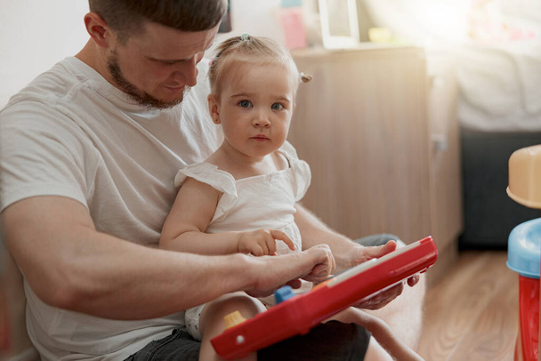 Handsome father with his child playing together using toys at home. Blurred background - Foto, Imagen