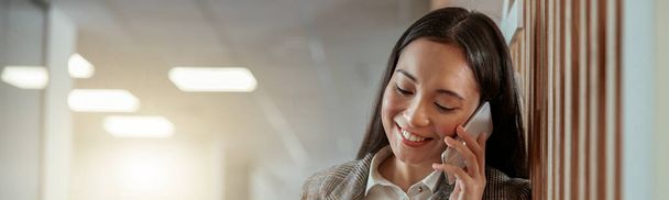 Asiatische Geschäftsfrau telefoniert mit Kunden und lächelt. Unklarer Hintergrund - Foto, Bild