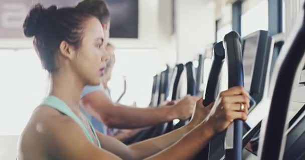 An active fitness woman exercising on a treadmill machine at a gym facility. Group of fit, serious and determined people running, jogging or training on modern equipment and keeping track of progress. - Felvétel, videó