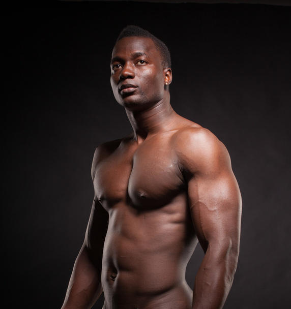 Beautiful and muscular black man in dark background - Foto, imagen