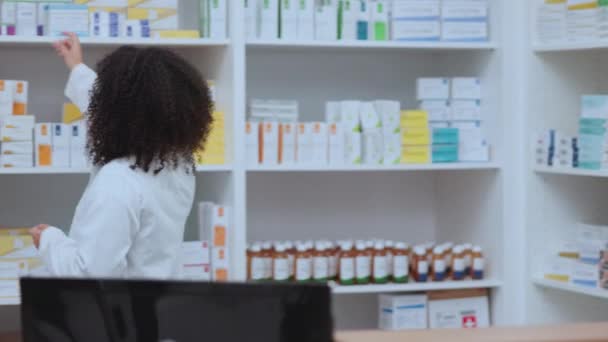 Pharmacist talking, helping and showing customer medicine in pharmacy and explaining prescription dosage. Medical healthcare professional with afro selling over the counter drugstore medication cream. - Filmati, video