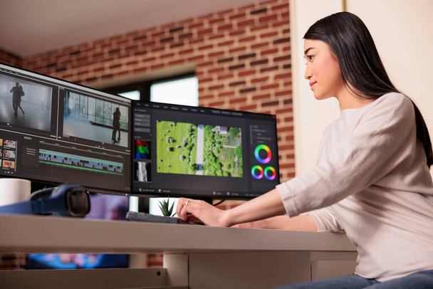 Asian videographer working on editing video and audio footage with professional software to create film content for post production. Using movie montage to edit multimedia movie. - Foto, Imagen