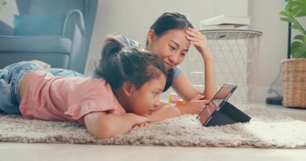 Азиатский малыш девочка дочь с мамой смотреть цифровой планшет на ковре пол весело, радостный момент в гостиной дома. Семья проводит время вместе, Концепция "Творческий образ жизни для ребенка". - Кадры, видео