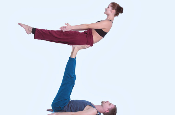 Young athletic couple practicing acroyoga. Balancing in pair. - Фото, зображення