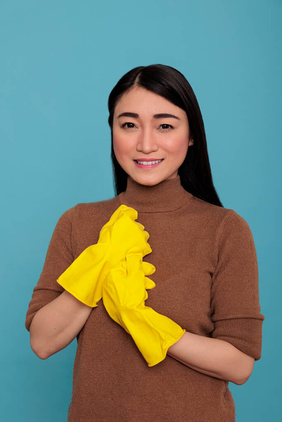 Adult glad satisfied asian housewife from work holding hand wearing rubber yellow gloves, Cleaning home concept, Happy optimistic and smiling woman with positive state of mind - Foto, imagen