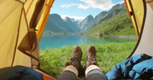 POV of a hiker or tourist camping on a field with nature view landscape on a beautiful sunny day with a lake, mountain in background. Hiking, adventure seeking person relaxing in Romsdalen, Norway. - Filmati, video