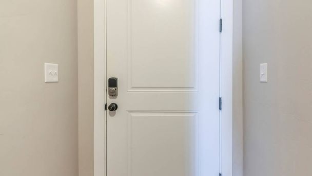 Panorama White fire door with a digital access to the garage. Interior of the house with light gray wall and dark wood flooring at the garage entrance. - Fotoğraf, Görsel