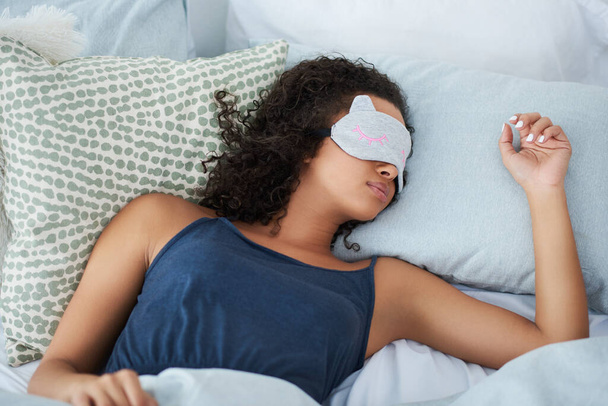 I sleep better with my eye mask on. an attractive young woman sleeping in bed with an eye mask during the morning - Valokuva, kuva