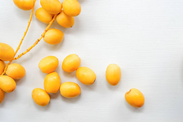 Fresh yellow dates on a white wooden floor, top view. - 写真・画像