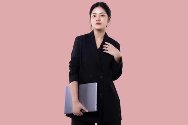 Young modern business asian woman holding laptop computer isolated over pink background. - Foto, afbeelding