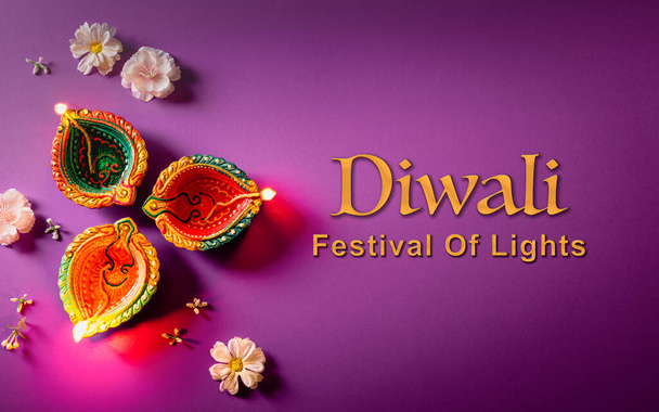 Happy Diwali - Clay Diya lámparas encendidas durante Dipavali, festival hindú de la celebración de las luces. Colorida lámpara de aceite tradicional diya sobre fondo púrpura - Foto, imagen
