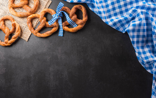 Oktoberfest festival decoration symbols made from Pretzel loaf and Bavarian white and blue fabric on dark stone background. - Foto, immagini