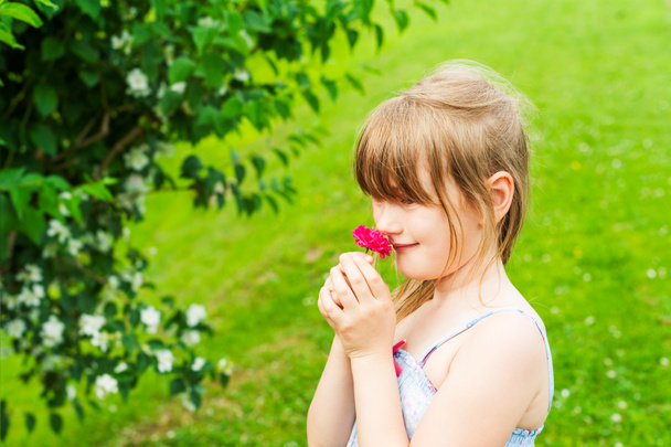 kleines Mädchen, das eine rosa Rose riecht - Foto, Bild