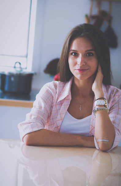 Young woman sitting near desk in the kitchen . - Fotografie, Obrázek