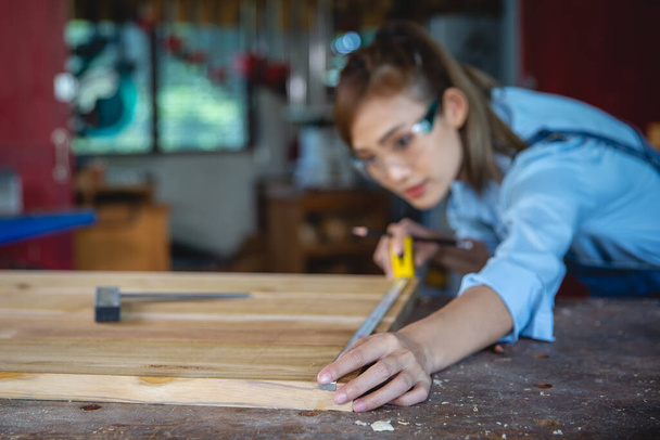 Женщина работает в столярной мастерской. Плотник, работающий на деревообрабатывающих станках в столярном цехе. - Фото, изображение