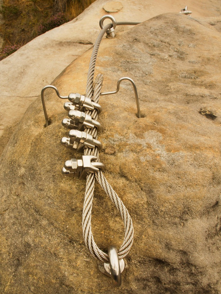 Cuerda retorcida de hierro fijada en bloque por tornillos ganchos a presión. Detalle del extremo de la cuerda anclado en piedra arenisca
  - Foto, imagen