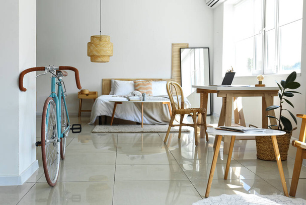 Interior of light bedroom with bicycle and workplace - Photo, Image