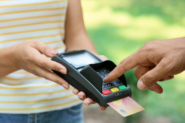Man paying with credit card via payment terminal outdoors, closeup - Fotoğraf, Görsel