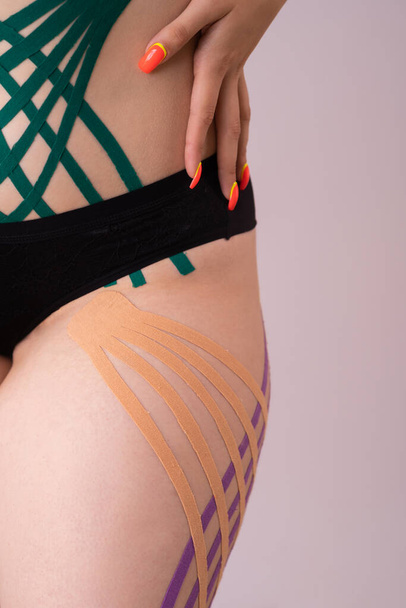 applying kinesiology tape to female patient legs.Kinesiology taping. Anti-cellulite procedure for slim hips.Fat lose, cellulite removal. Weight loss concept. - Photo, image
