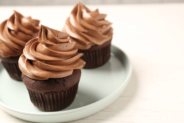 Delicious fresh chocolate cupcakes with cream on white table, closeup - Photo, image