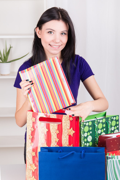 Smiling happy girl prepares bags gifts for Christmas - Zdjęcie, obraz
