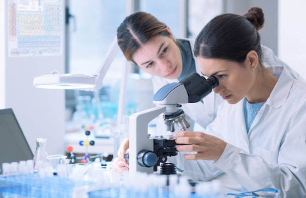 Young female researchers working together in a medical lab, they are examining samples with a microscope - Fotografie, Obrázek