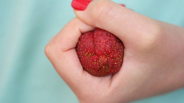 Clenched strawberries in fist in form of constipation of colon. Hemorrhoids acute symptoms and treatment - Fotoğraf, Görsel