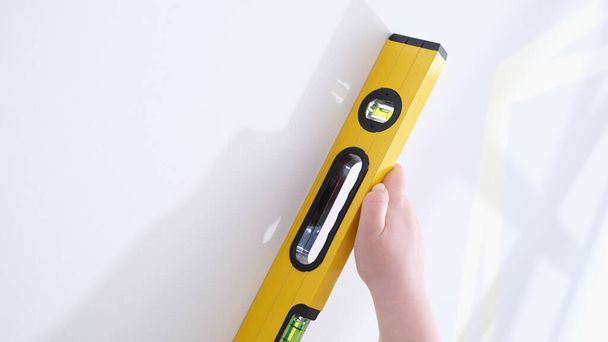 Professional yellow measuring device for level and evenness of wall. Builder makes repairs in apartment concept - Fotó, kép