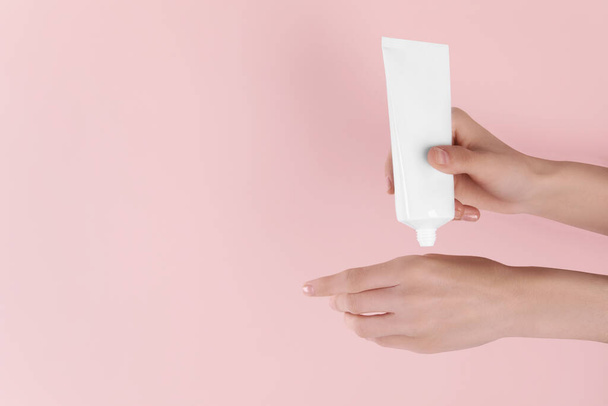Woman applying cream onto hand on pink background, closeup. Space for text - Φωτογραφία, εικόνα