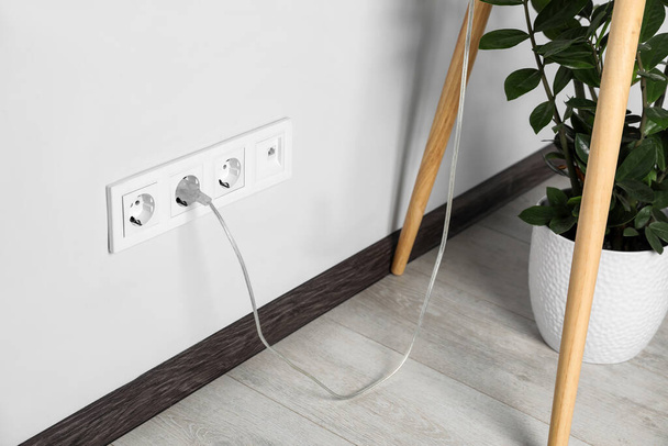 Power socket and plug on wall indoors. Electrician's equipment - Foto, afbeelding