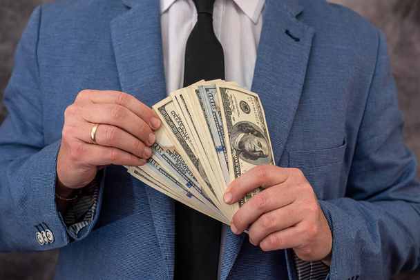 a university lecturer in a suit takes bribes in dollars and hides money in his pocket. The concept of large bribes in educational institutions - Fotoğraf, Görsel