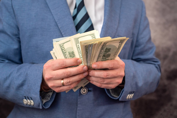 Business man on day holdings with dollar banknotes in his hands. Finance concept - Foto, Imagem