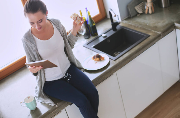 Smiling woman online shopping using tablet and credit card in kitchen . - Photo, image