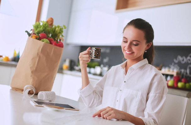 Smiling woman online shopping using tablet and credit card in kitchen . - Foto, Imagen