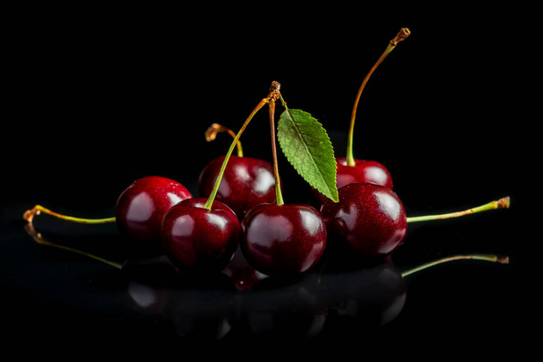 Sweet cherries with cherry leaf on a black background - Photo, image