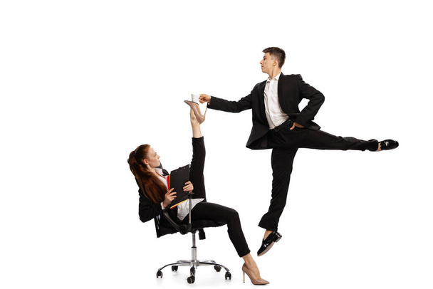 Co-workers. Modern business world, lifestyle. Two stylish office workers in business suits in action isolated on white background. Art, beauty, fashion and business concept. Copy space for ad - Zdjęcie, obraz