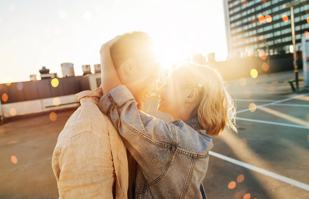summer holidays, love and people concept - happy young couple hugging on roof top city parking - Fotoğraf, Görsel