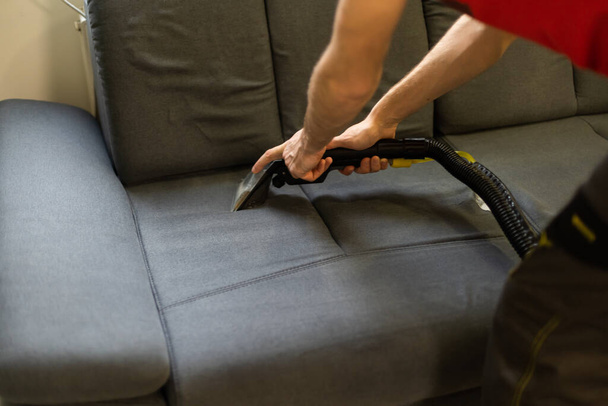 Чоловік хімчистки працівник прибирає диван з професійним методом видобутку
. - Фото, зображення