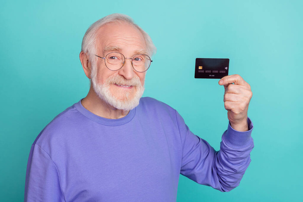 Portrait of friendly satisfied aged man hand hold plastic debit card toothy smile isolated on teal color background. - Φωτογραφία, εικόνα