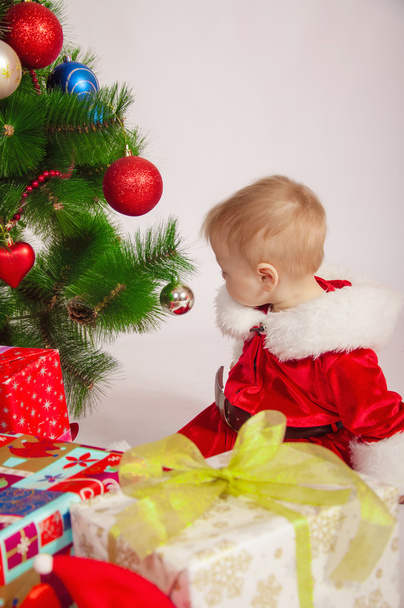 Baby in Santa costume at the Christmas tree - Foto, afbeelding