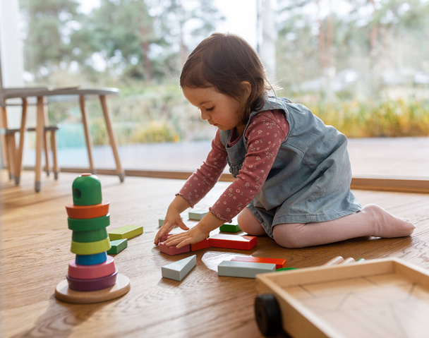 childhood, hygge and people concept - little baby girl playing with toy blocks at home - Zdjęcie, obraz