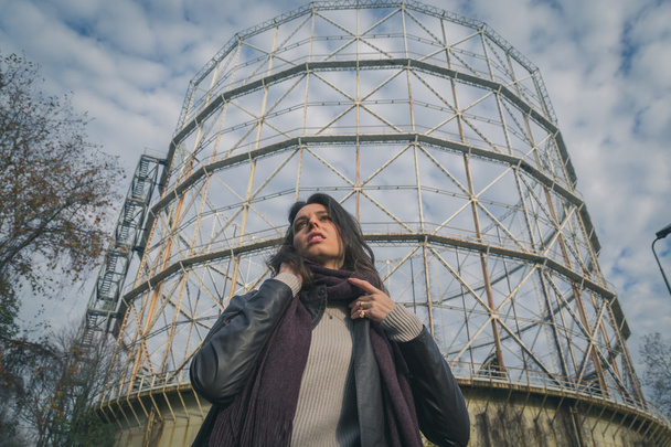 Beautiful young brunette posing in front of a gasometer - Foto, Bild
